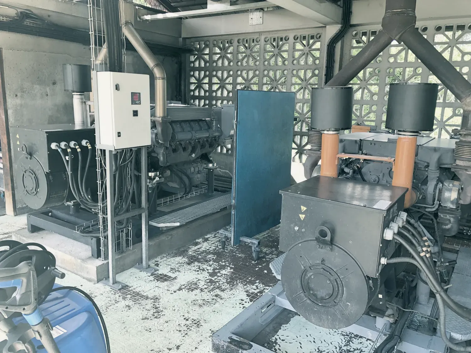 Photo jointe au relevé : deux groupes électrogènes sous un abri aux murs ajourés, avec leur armoire électrique.